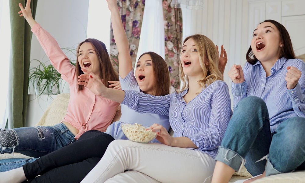 4 teenage girls exclaiming in joy at the TV